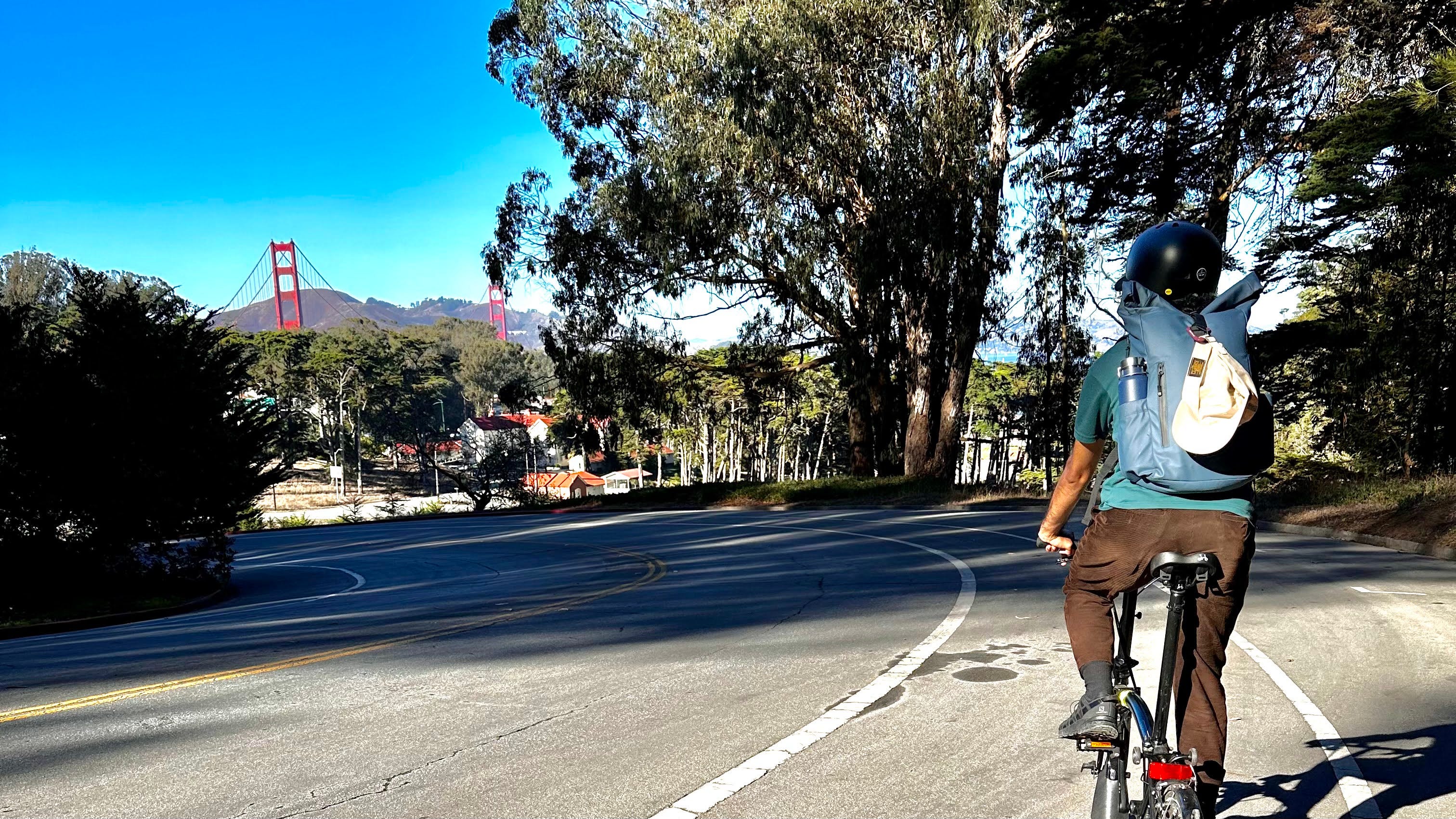 Photograph of author riding my bicycle down a hill. Golden Gate Bridge in the distance.